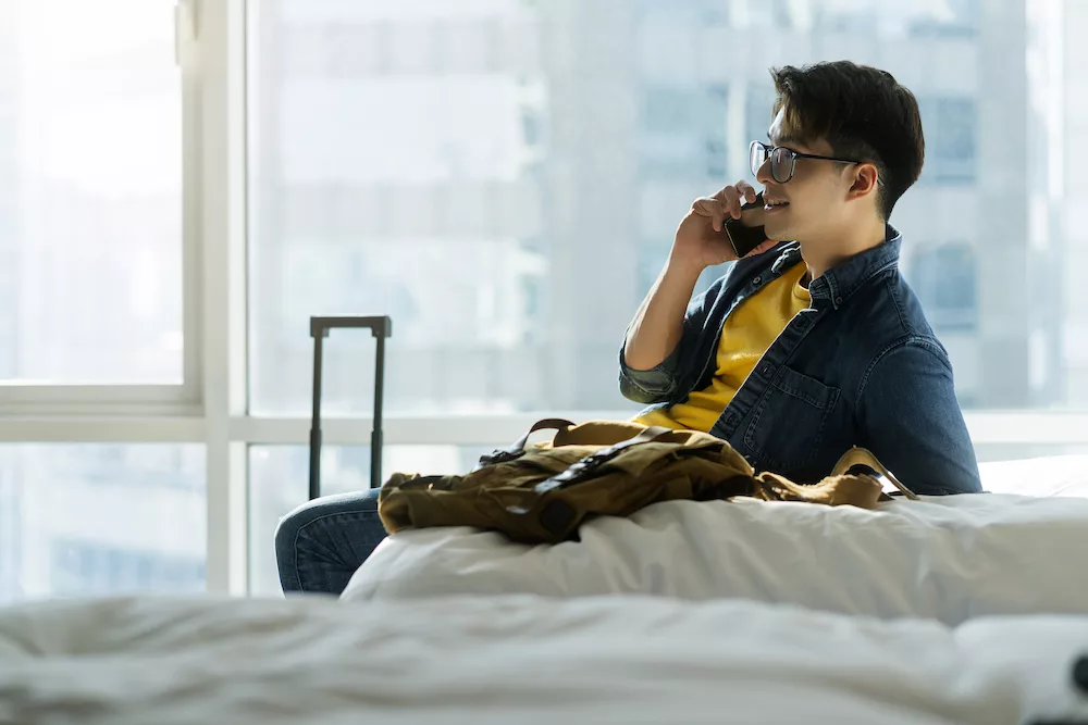 man in a hotel room talking to someone using his phone