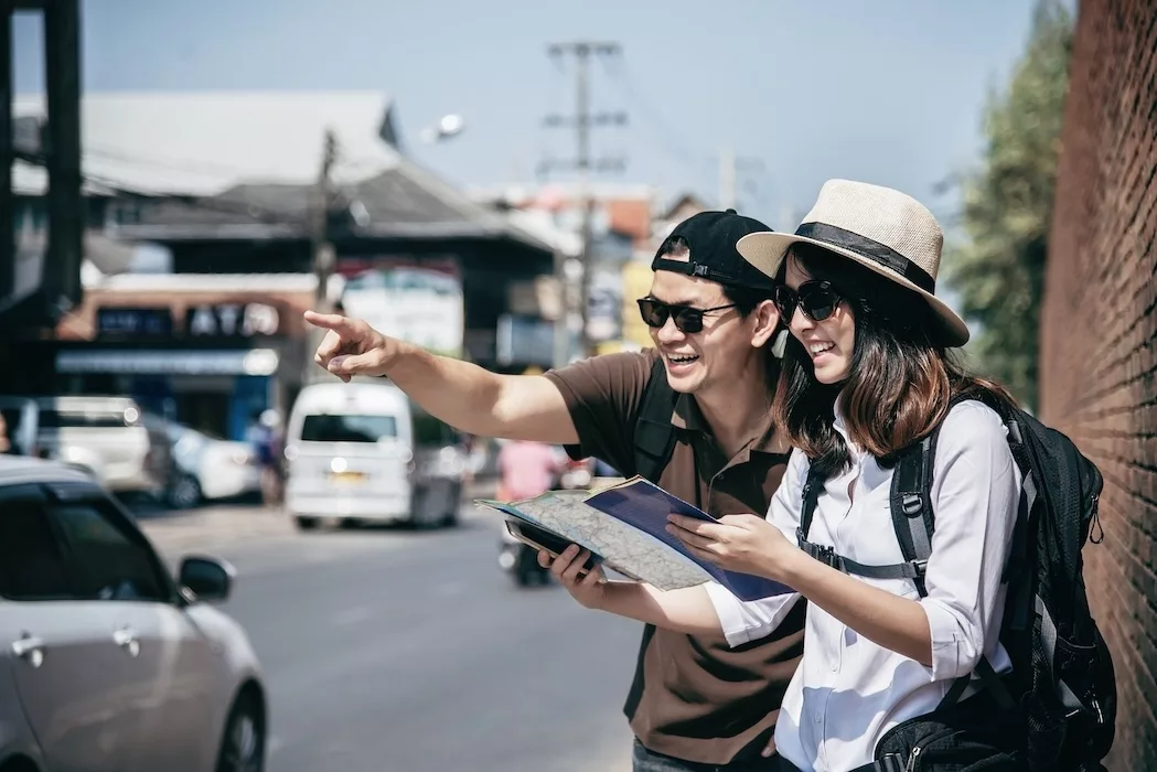 couple tourist holding city map crossing the road