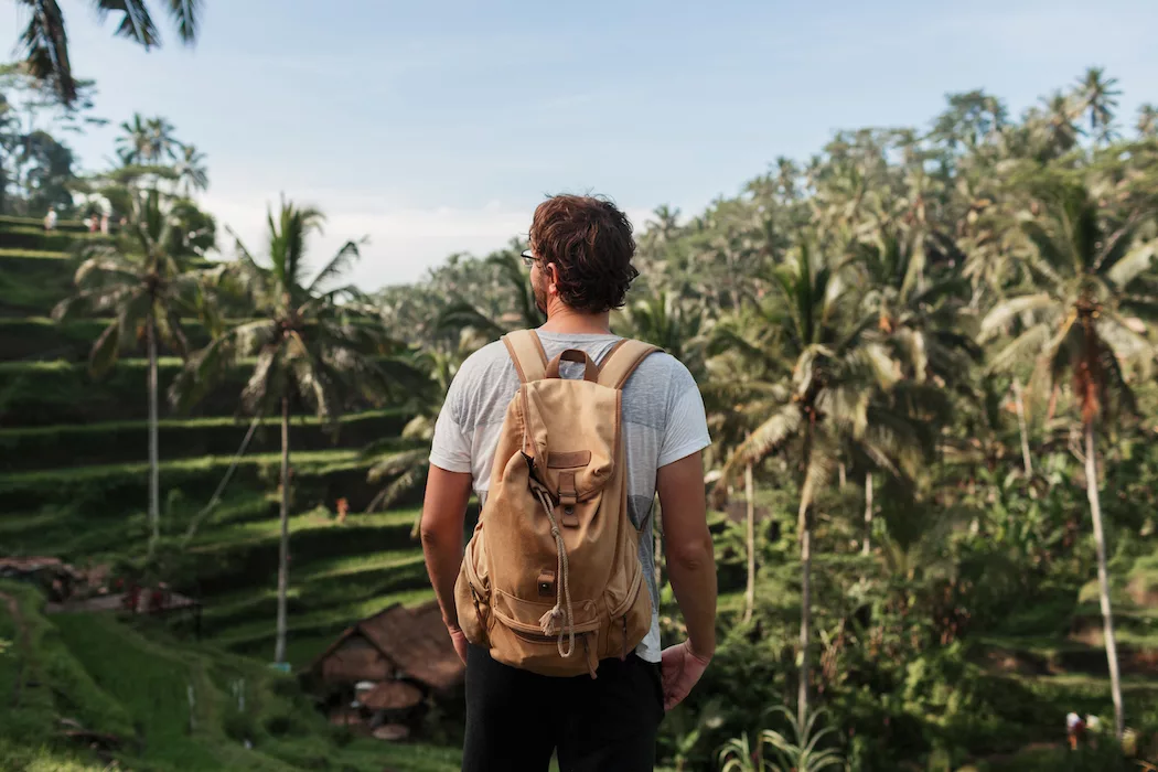 Back view of man explorer with travel backpack enjoying natural environment