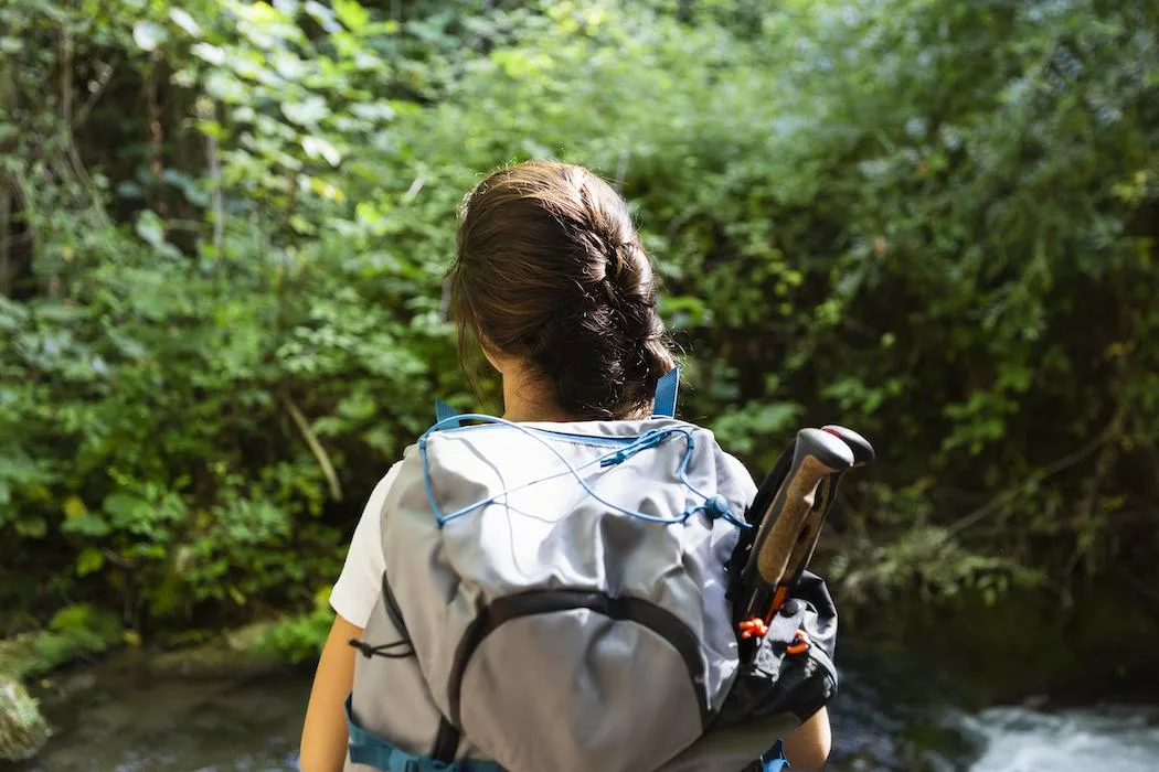 back view of a woman with backpack exploring nature